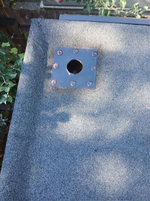 Gray speckled stone surface with a small blue metal plate and round hole near the top left.
