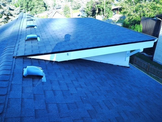Blue shingled roof with a large white vent cover and a small rooftop skylight, viewed from above