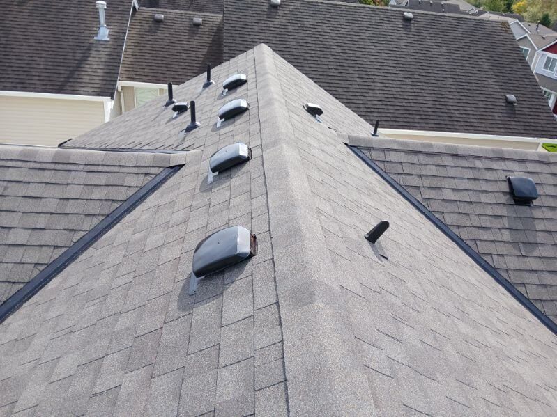Rooftop with gray shingles and several black vents on a sloped roof