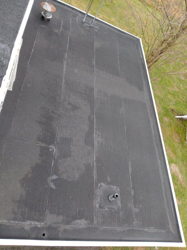 Flat black rooftop with vents and a gravel border, seen from above.
