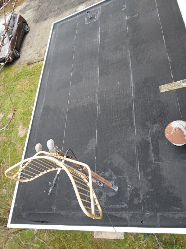 Overhead view of a black rooftop or patio with a curved ladder or slide-like structure and a brown ball-like object.