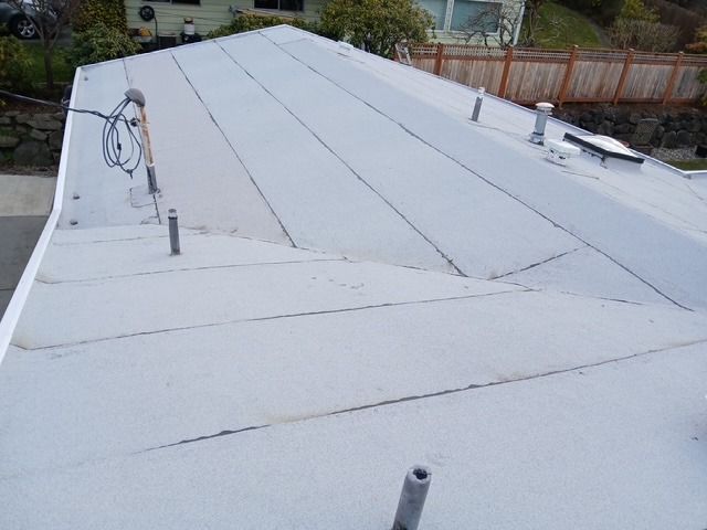 White metal roof with vents and cables, viewed from above.