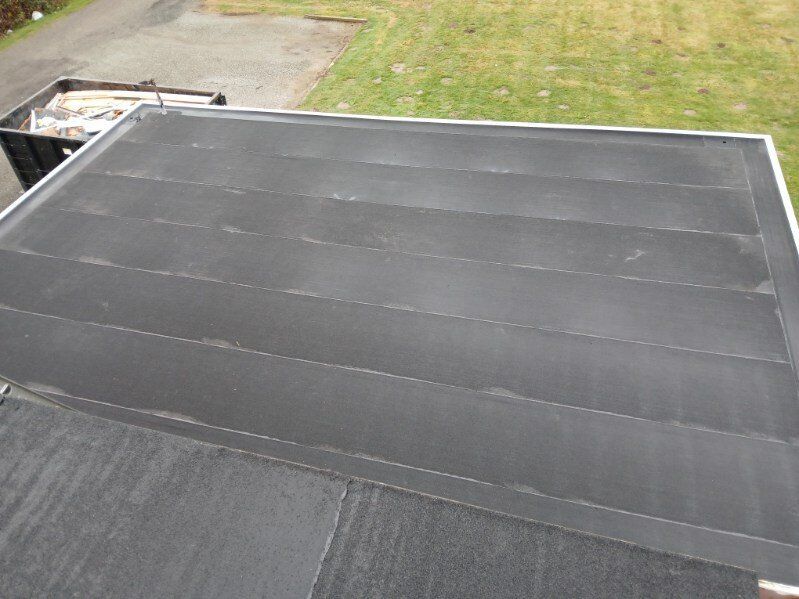 Flat black rooftop with rows of dark solar panels on a building