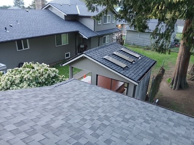 Rooftops and backyard view with a small shed, trees, and neighboring houses in a residential area