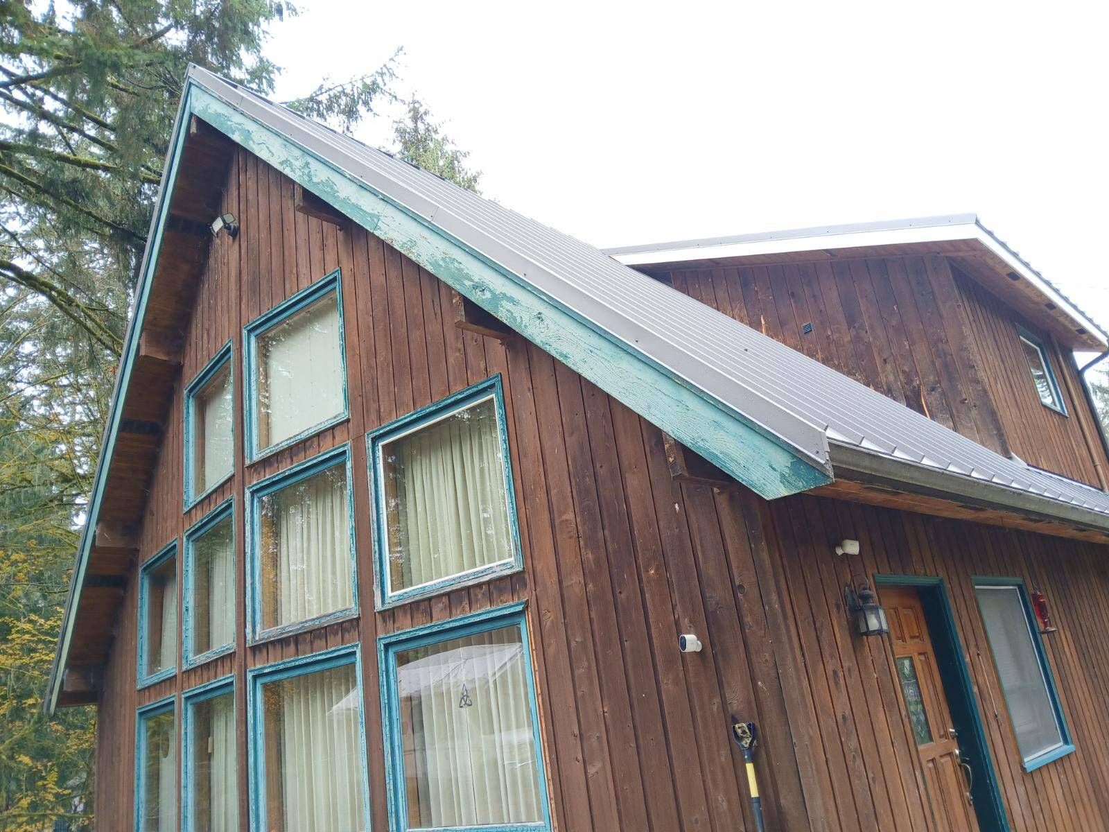 Wooden cabin with steep roof and tall windows, viewed from outside among trees