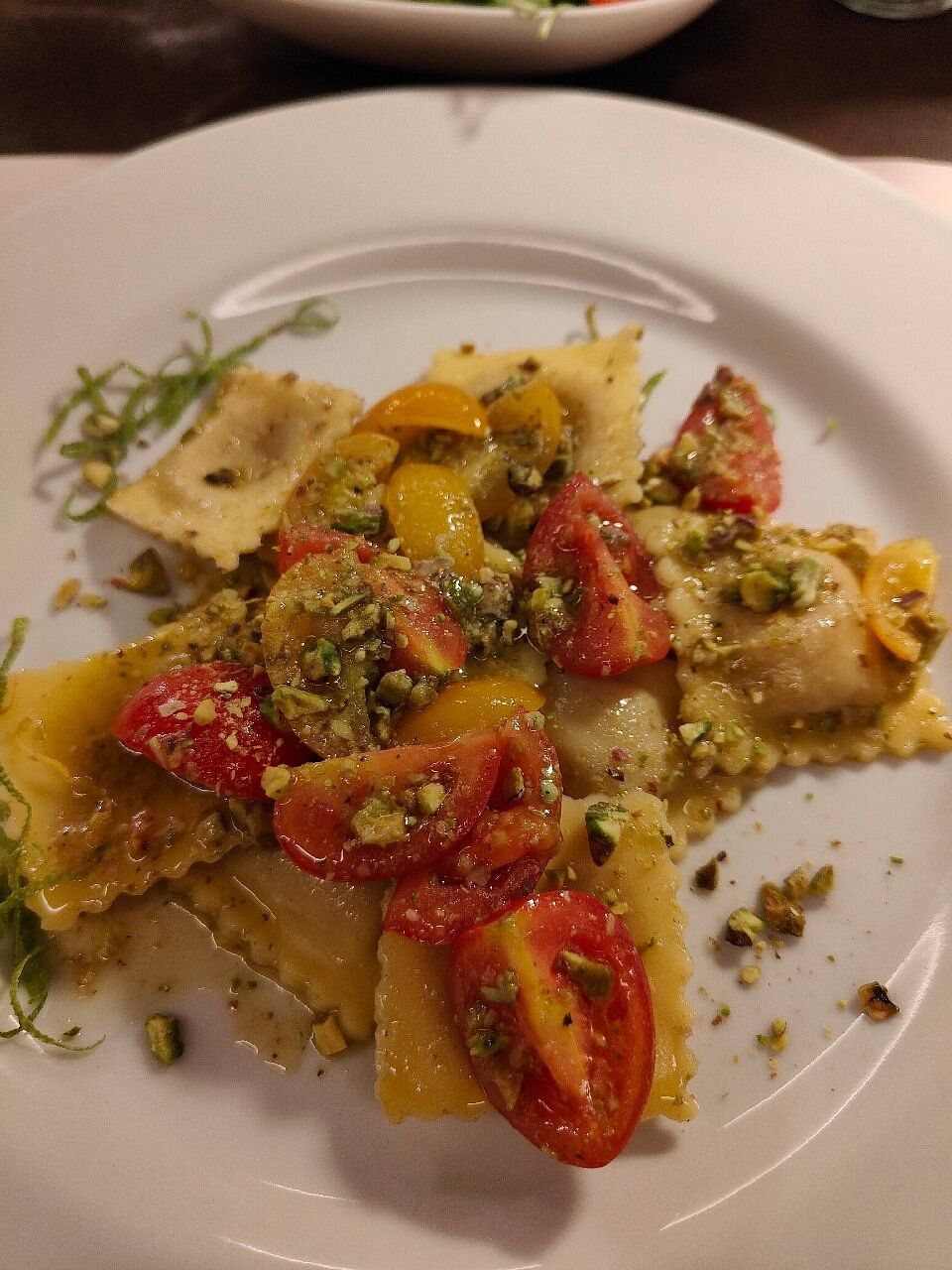 Interno di un ristorante moderno con tavoli, sedie e piante su pareti grigie e gialle.
