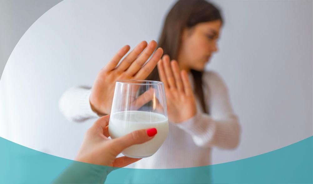 Una persona che rifiuta un bicchiere di liquido bianco offerto da un'altra mano, a indicare un'avversione o una restrizione alimentare.