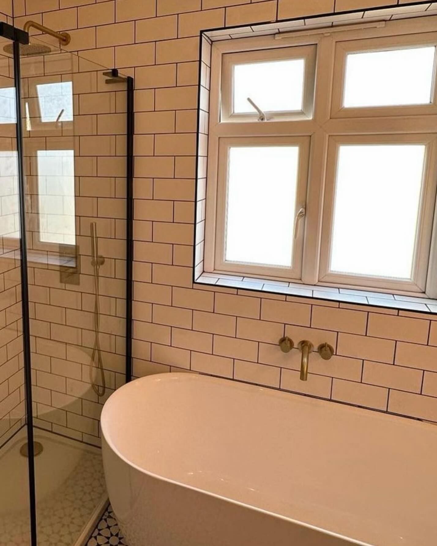 Pink bathtub and white tiled bathroom wall with window and mirror reflections