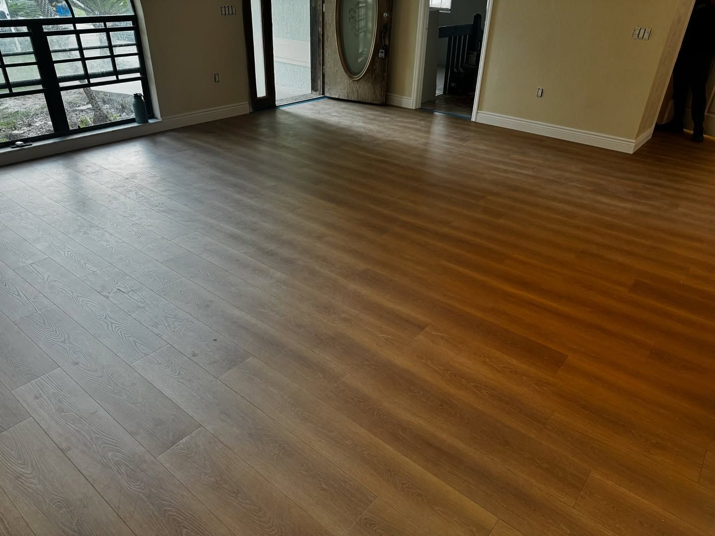 Empty room with wood-look flooring and large windows letting in natural light
