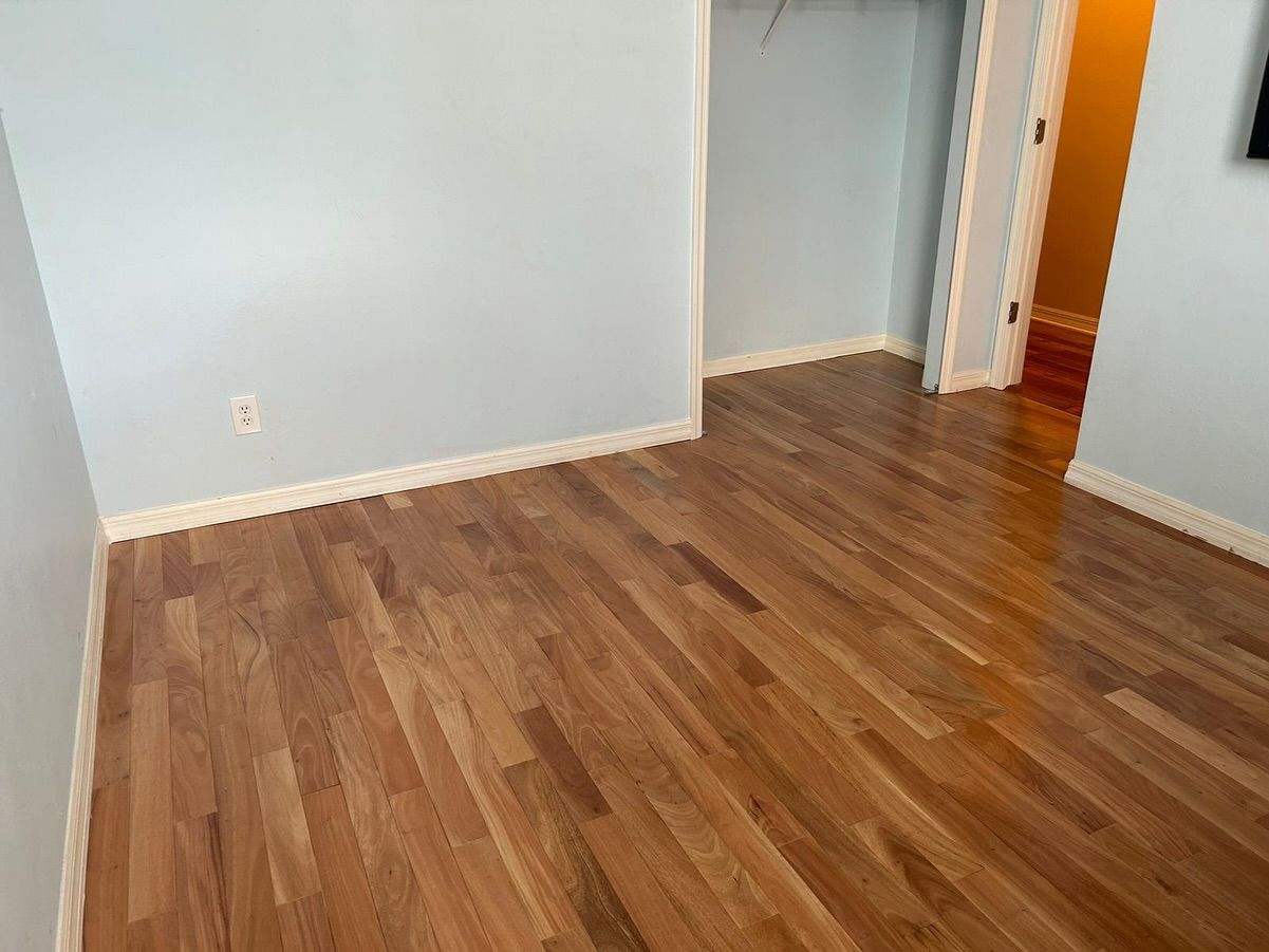 Empty room with light gray walls, wood flooring, and an open doorway to a hall.