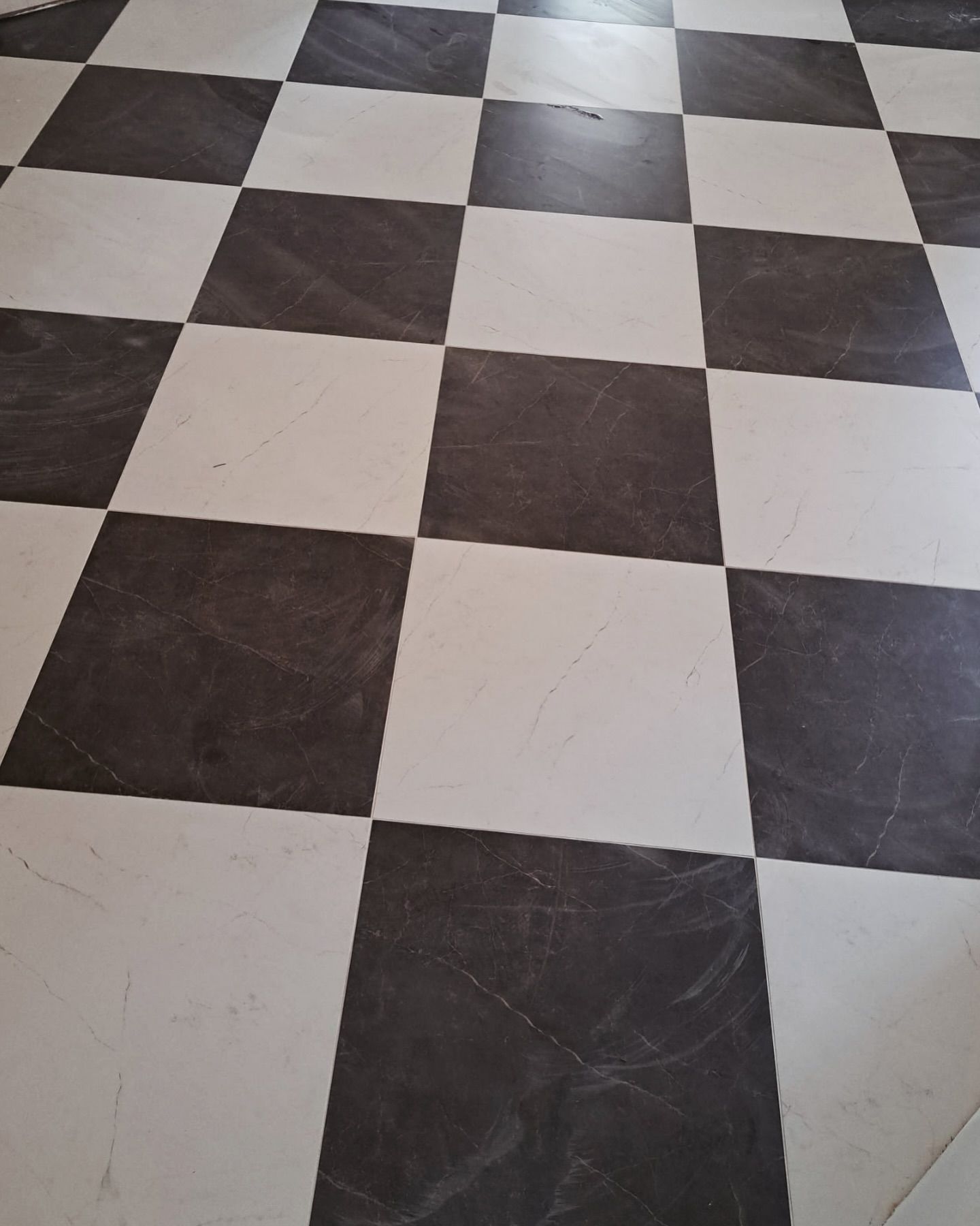 Black-and-white checkered tile floor viewed at an angle, with visible wear and scratches.