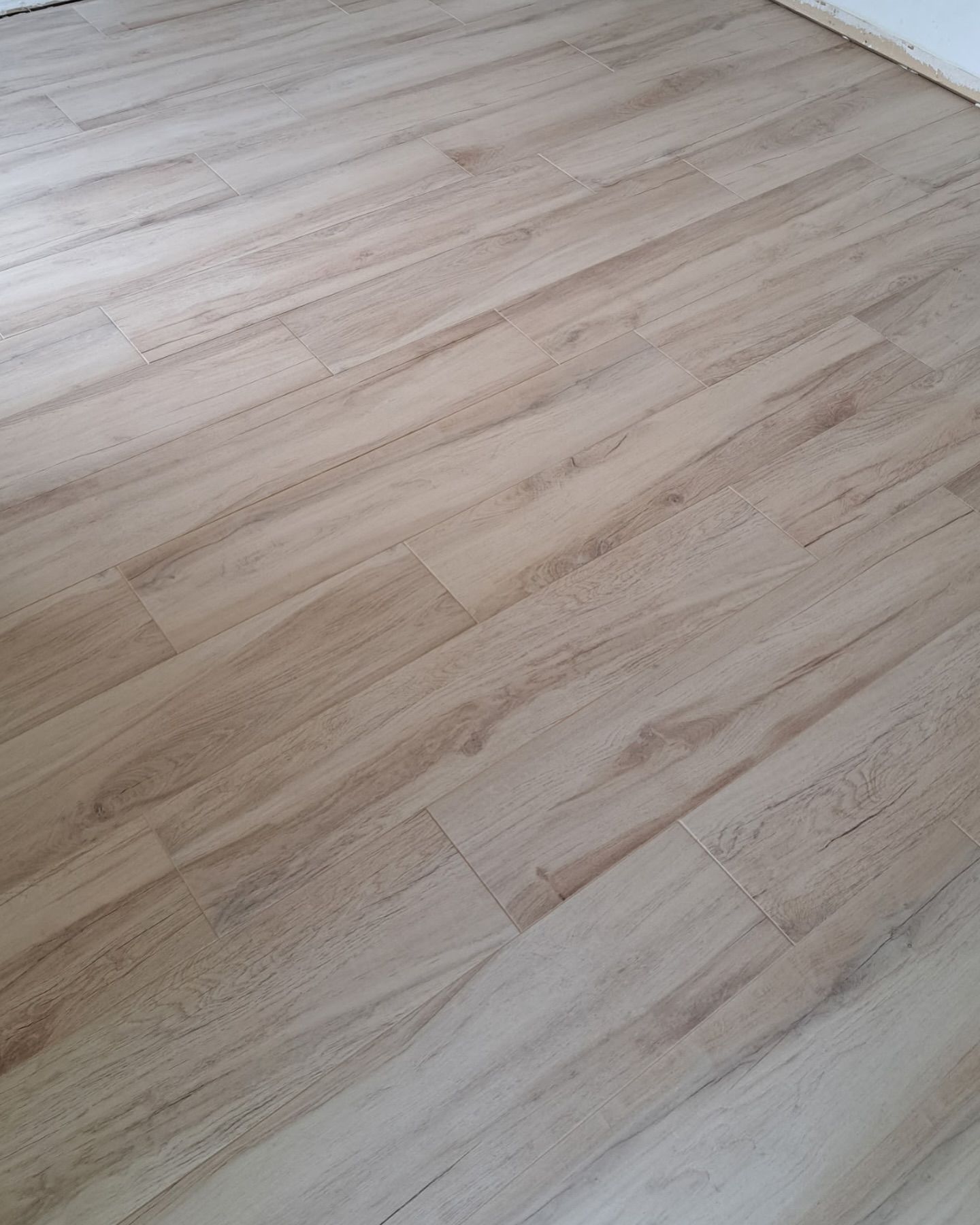 Light wood laminate flooring in an empty room, shown from above.