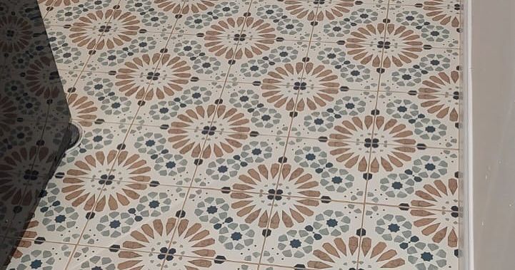 Patterned tile floor with beige, teal, and terracotta floral motifs, viewed from above