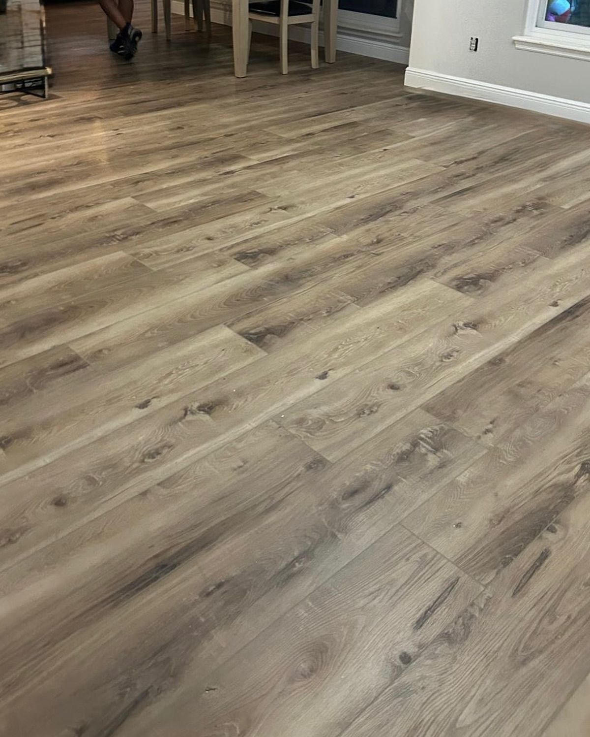 Wood-look vinyl flooring in a bright room with dining furniture in the background