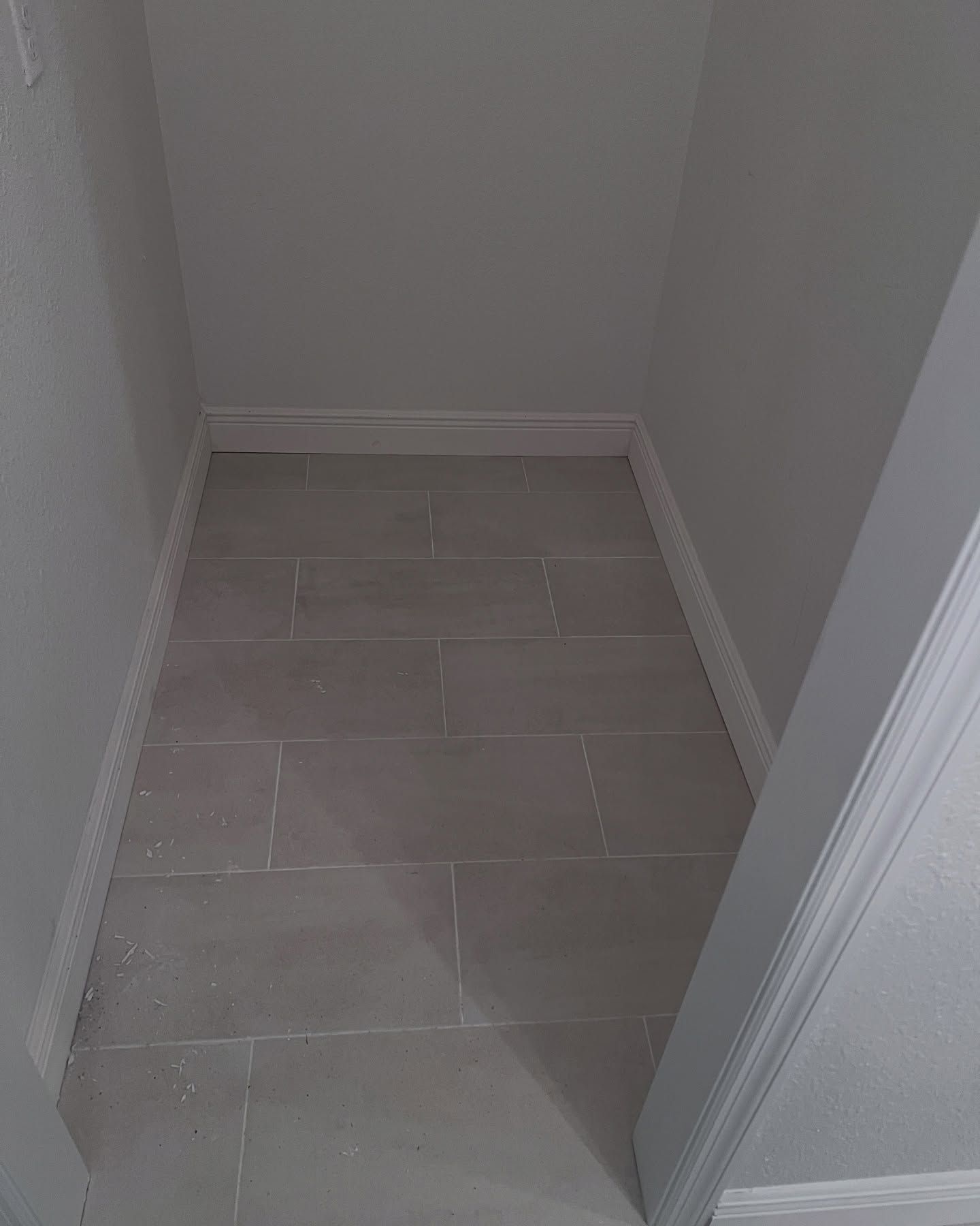 Narrow empty tiled hallway nook with light gray walls and white trim.
