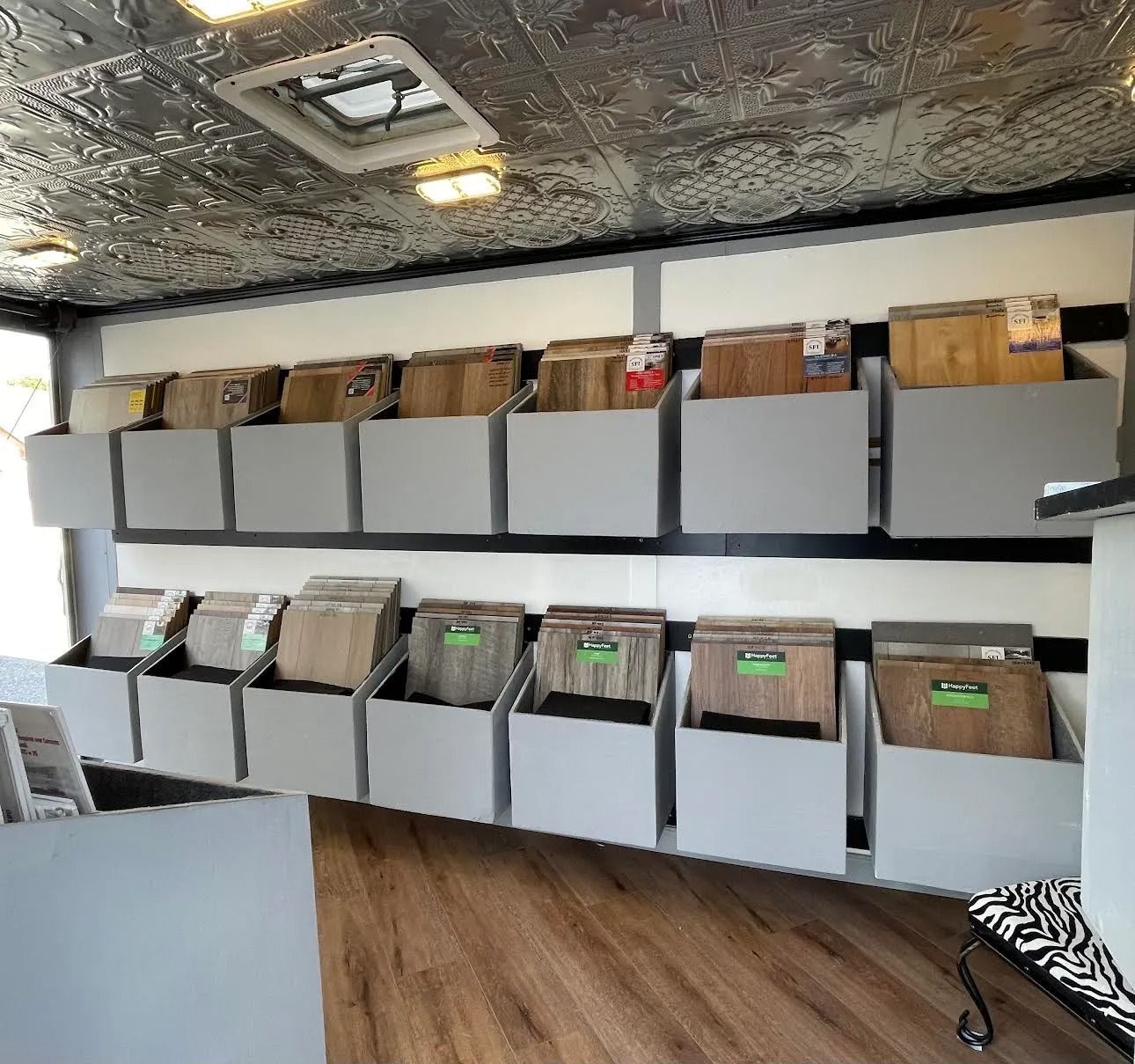 Rows of hanging file bins in a mobile office or storage van with gray cabinets and wood flooring.