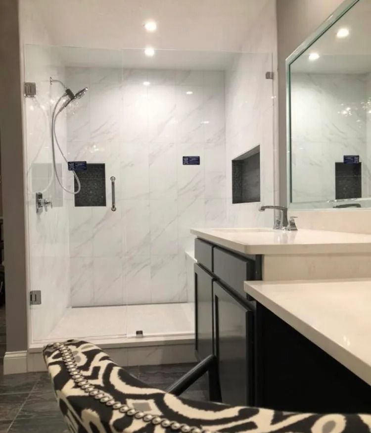 Modern bathroom with walk-in shower, large vanity mirror, and patterned black-and-white rug.