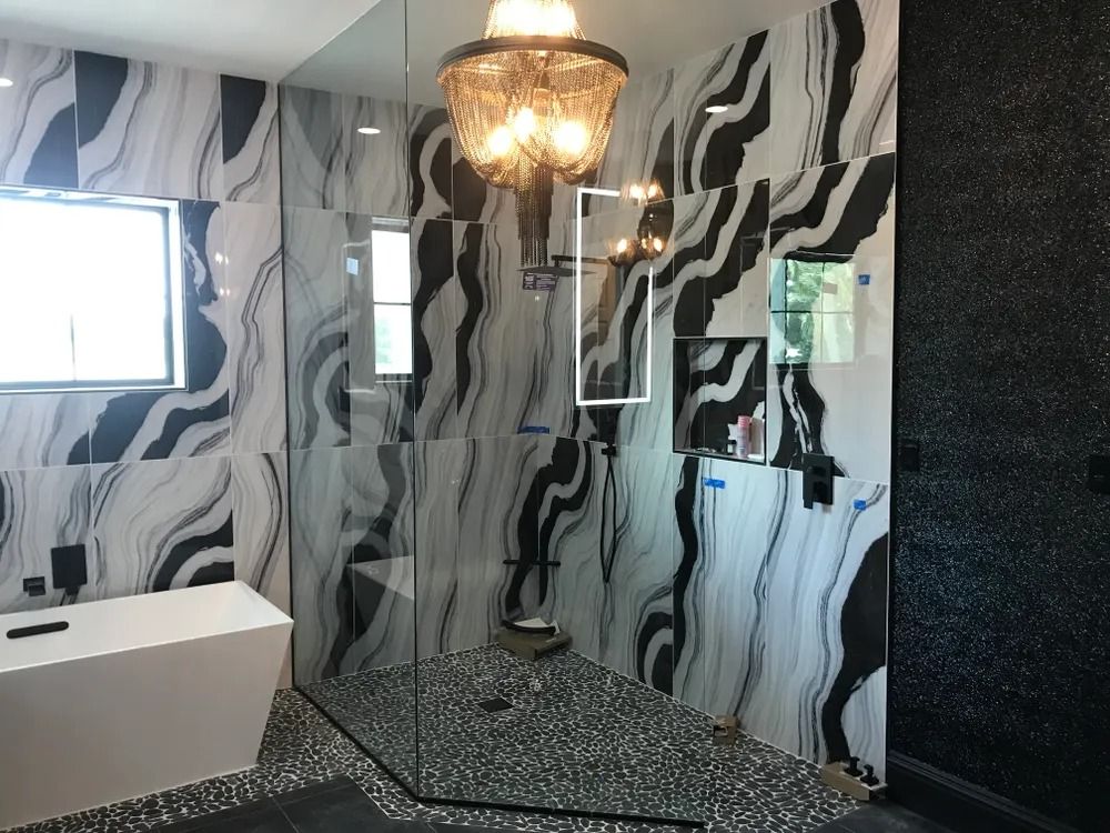 Modern bathroom with black-and-white wavy wallpaper, chandelier, mirror, and white sink.