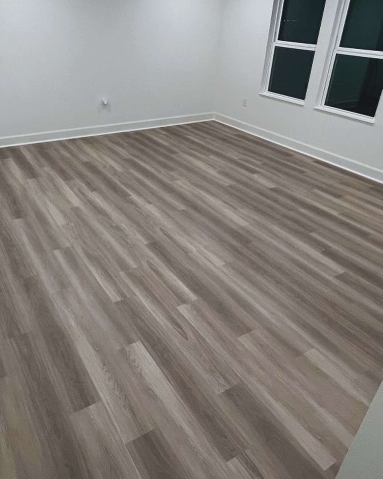 Empty room with gray wood-look flooring, white walls, and a windowed door.