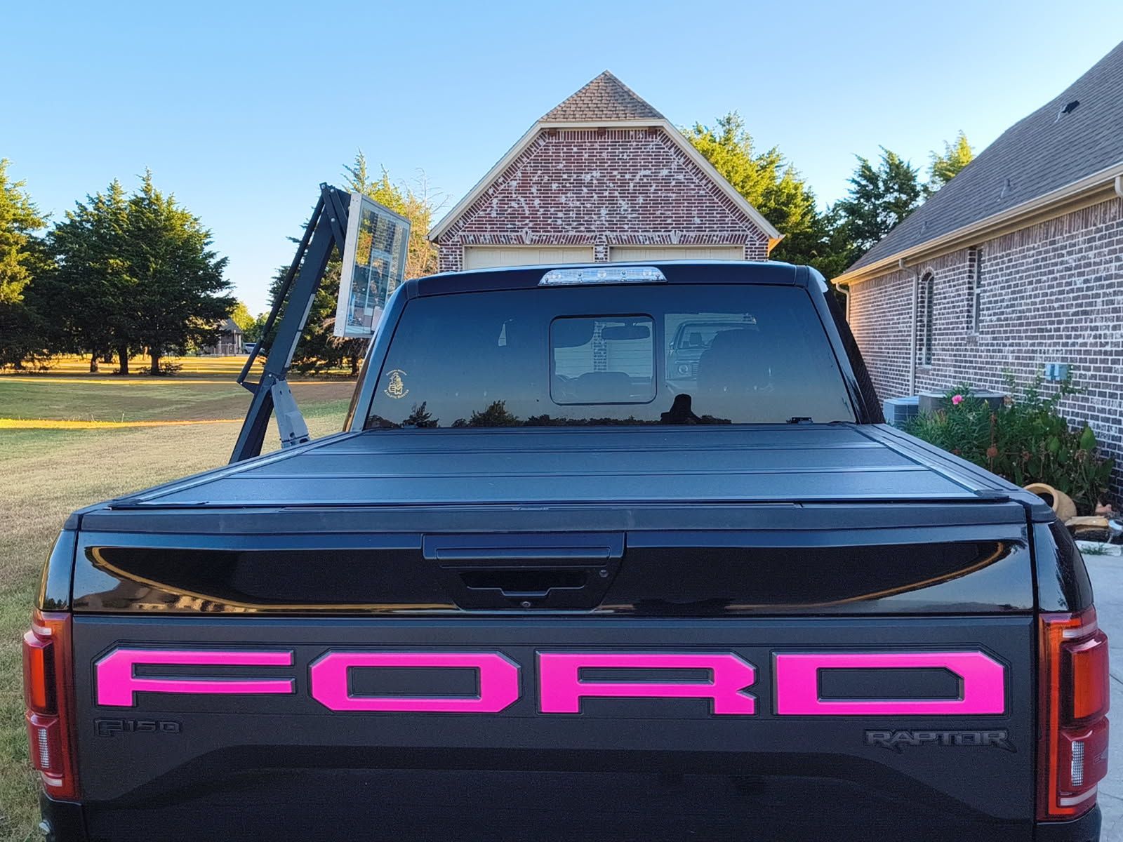 Pink Ford truck parked between thatched-roof buildings, front view in daylight