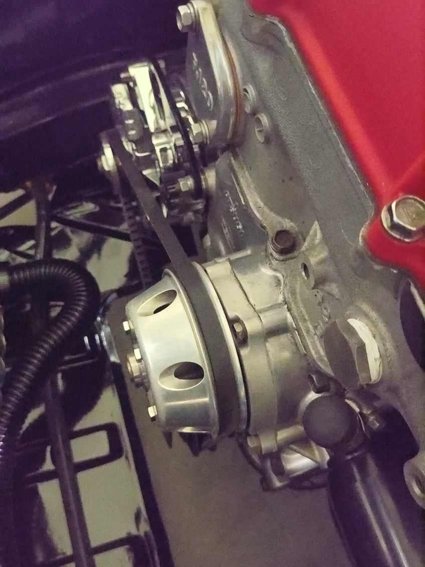 Close-up of a motorcycle engine assembly with silver metal parts and a red body panel