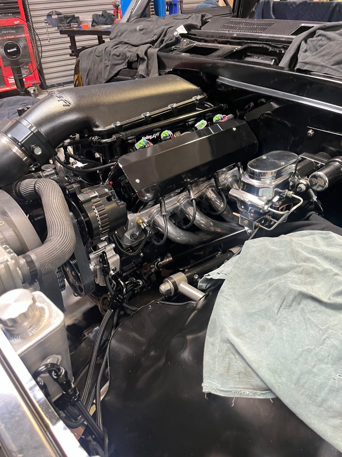 Car engine bay with a large intake manifold and exposed components, partially covered by a towel.