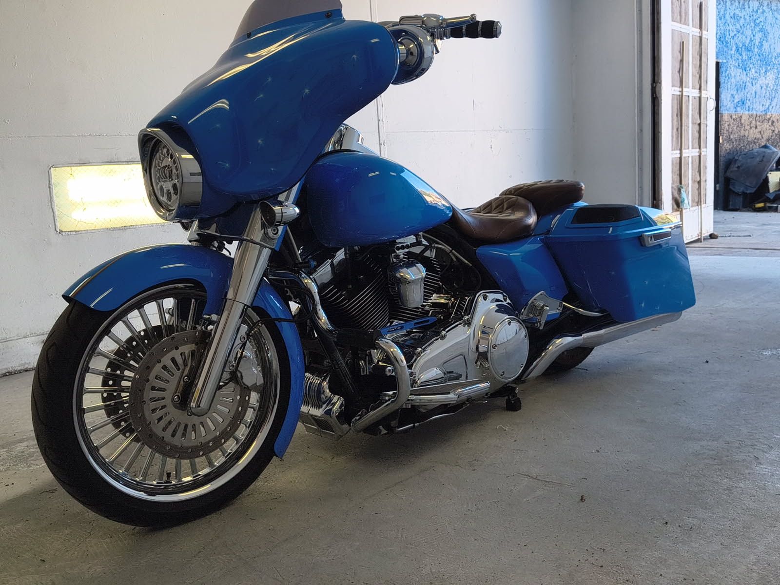 Blue touring motorcycle parked in a garage, viewed from the front-left side.