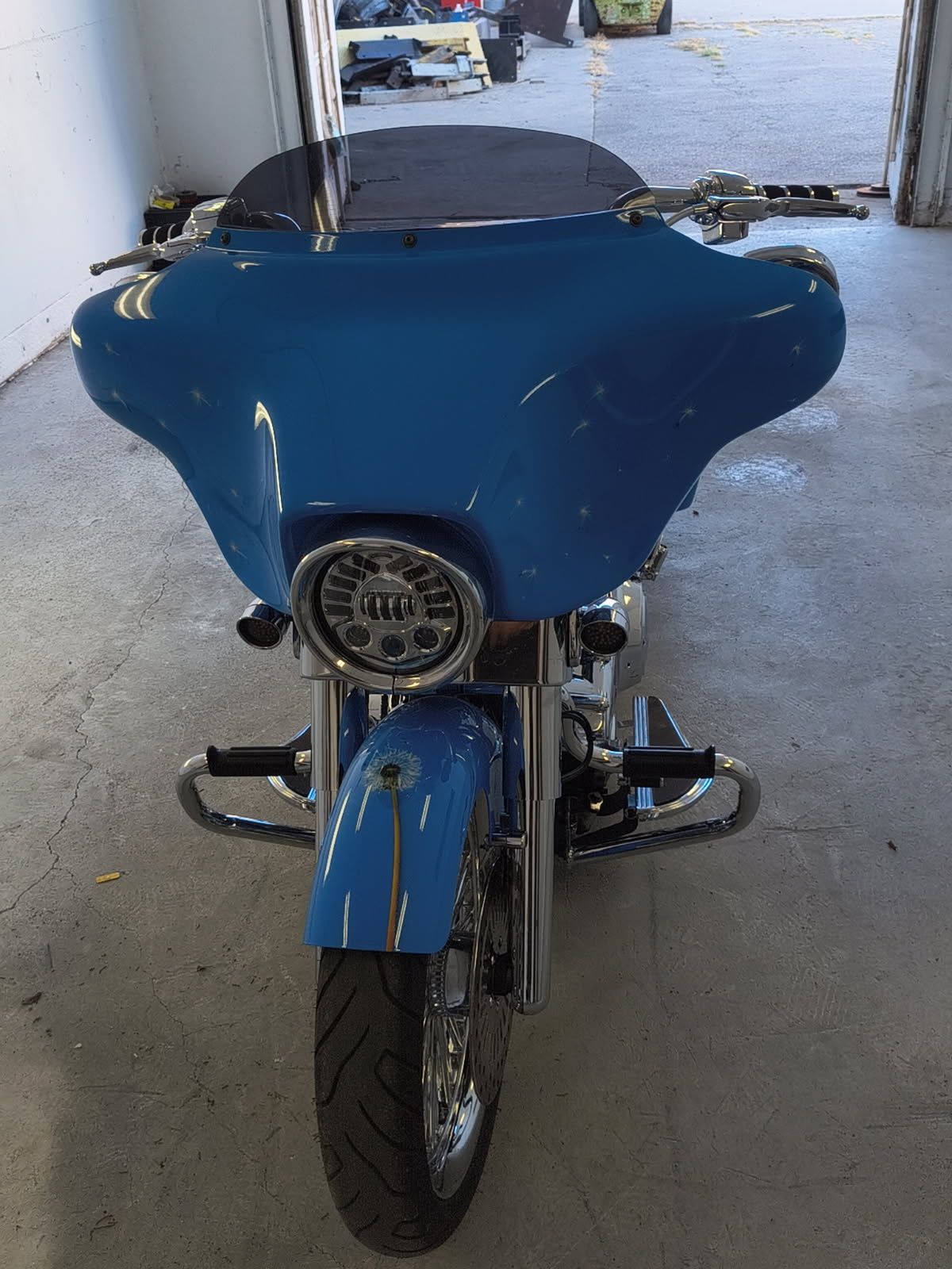 Blue motorcycle with a large front fairing parked indoors, viewed from the front.