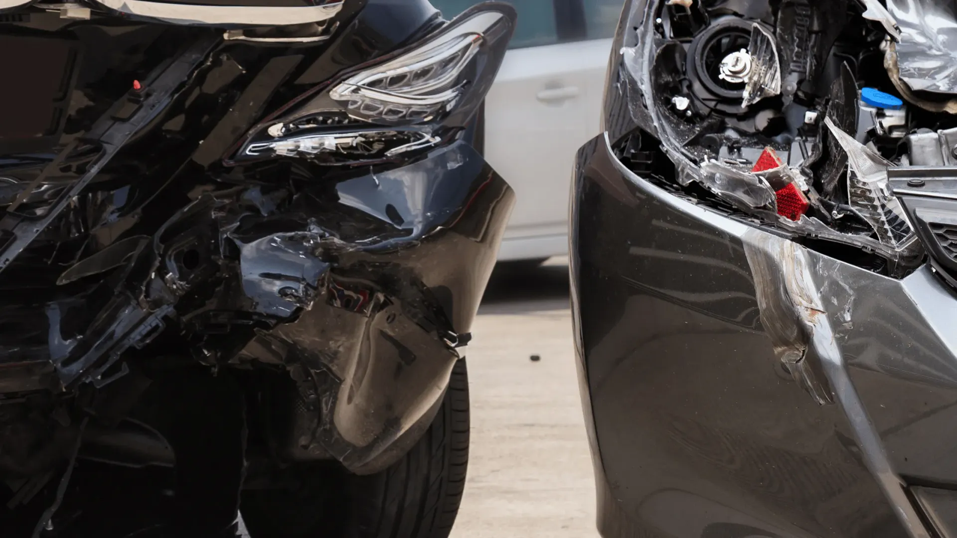 Two black cars with severe front-end collision damage, showing crumpled bumpers and exposed parts