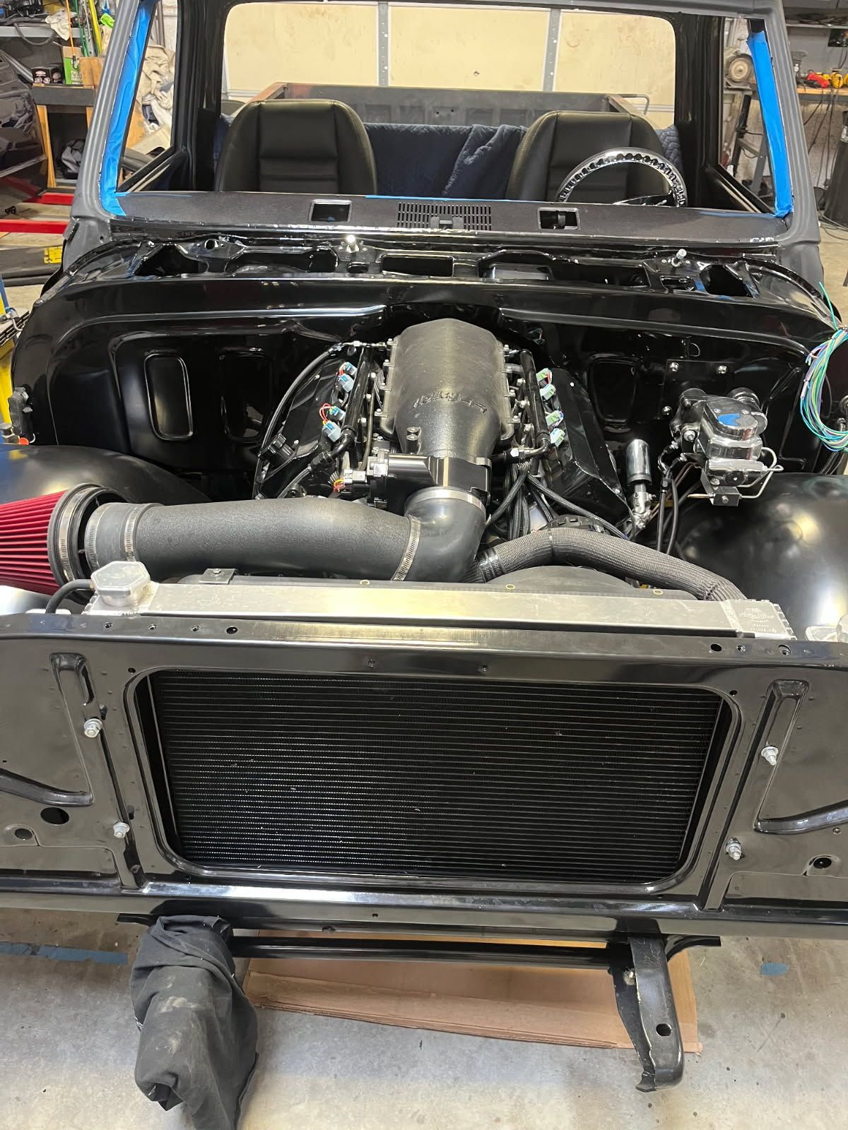 Black off-road vehicle with exposed engine and front grille in a garage or workshop