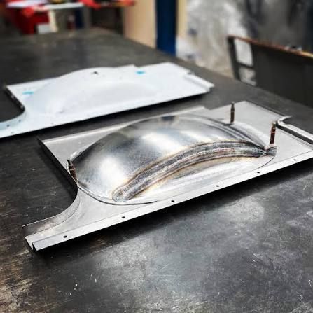 Metal mold with a shiny domed part on a black workbench in a workshop