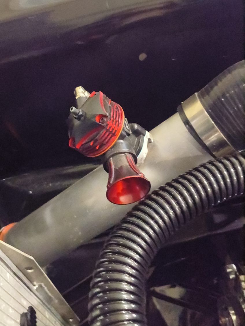 Red and black valve mounted on a gray pipe amid black tubing and wiring.