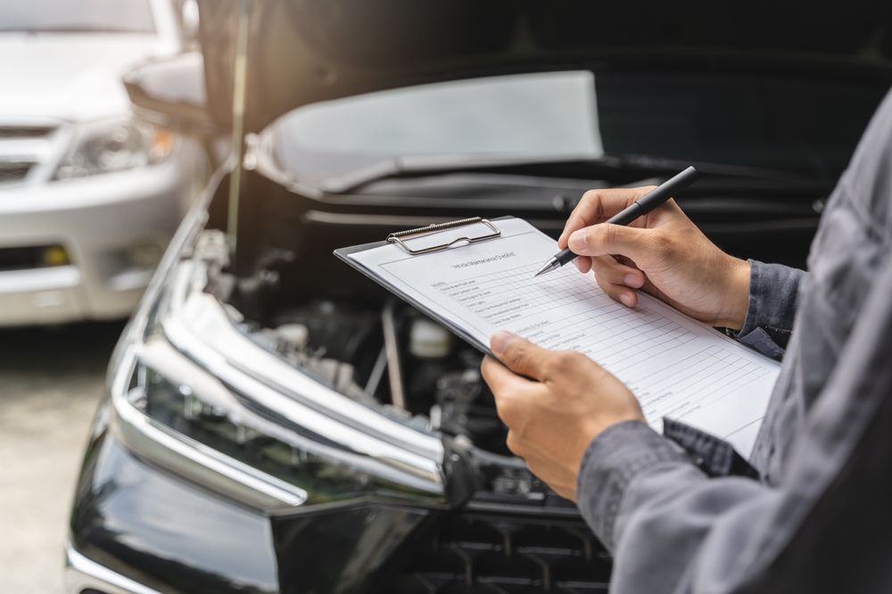 Person filling out a vehicle inspection form beside a black car with the hood open