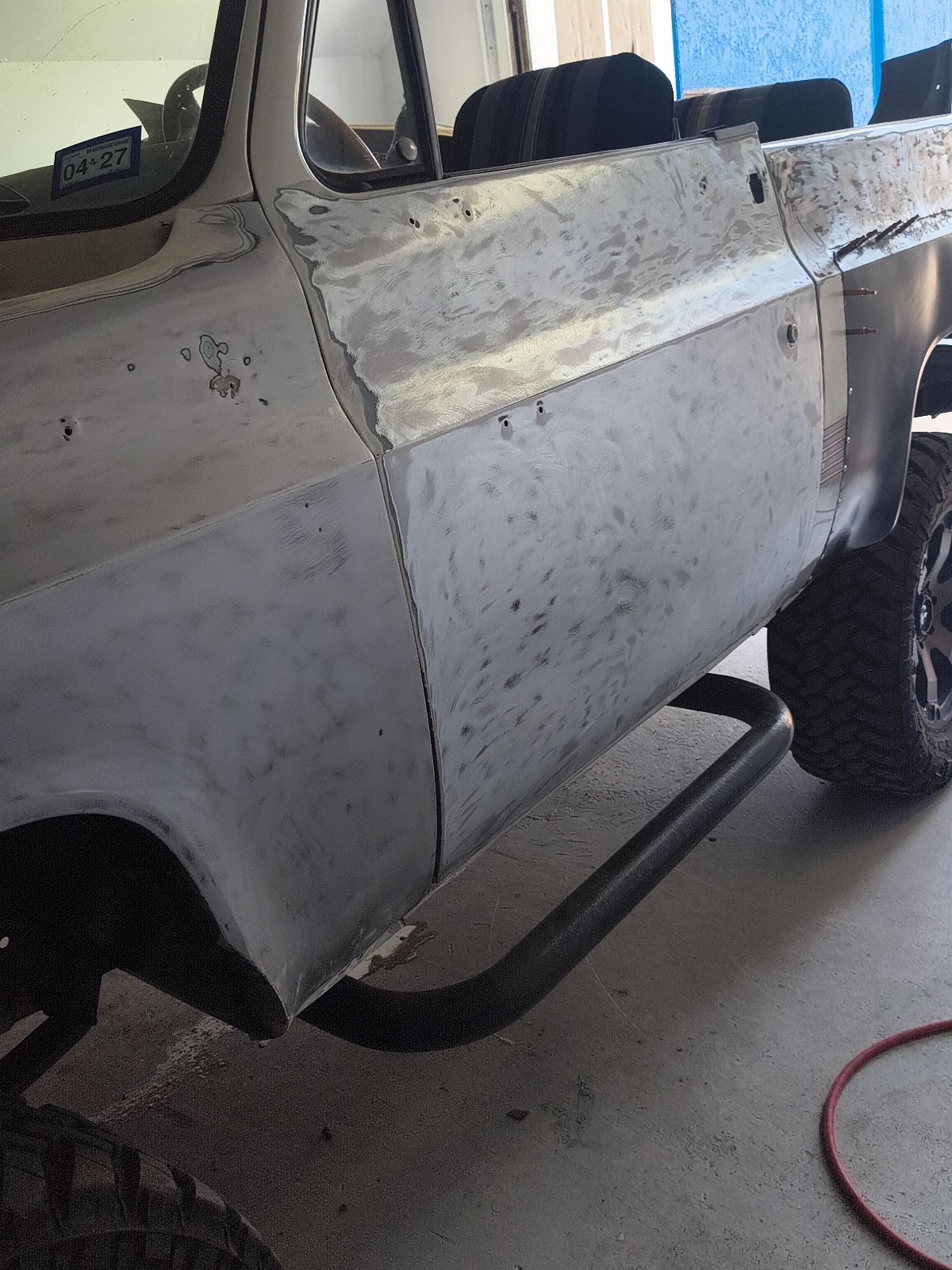 White off-road truck with visible dents and scratches in a garage, side view.