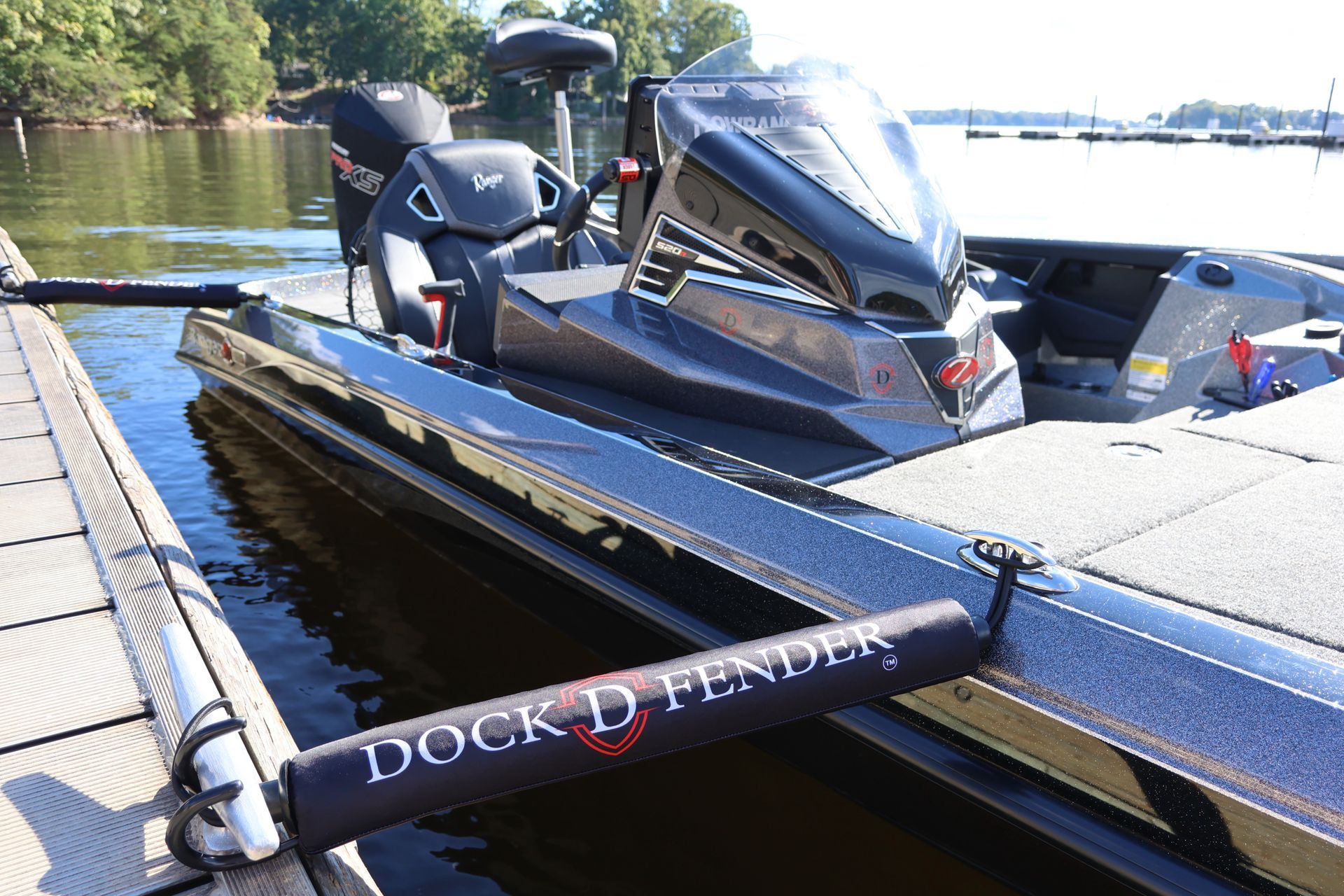 Bass boat docked at a wooden pier, featuring two gray and red seats, a motor, and fishing equipment.