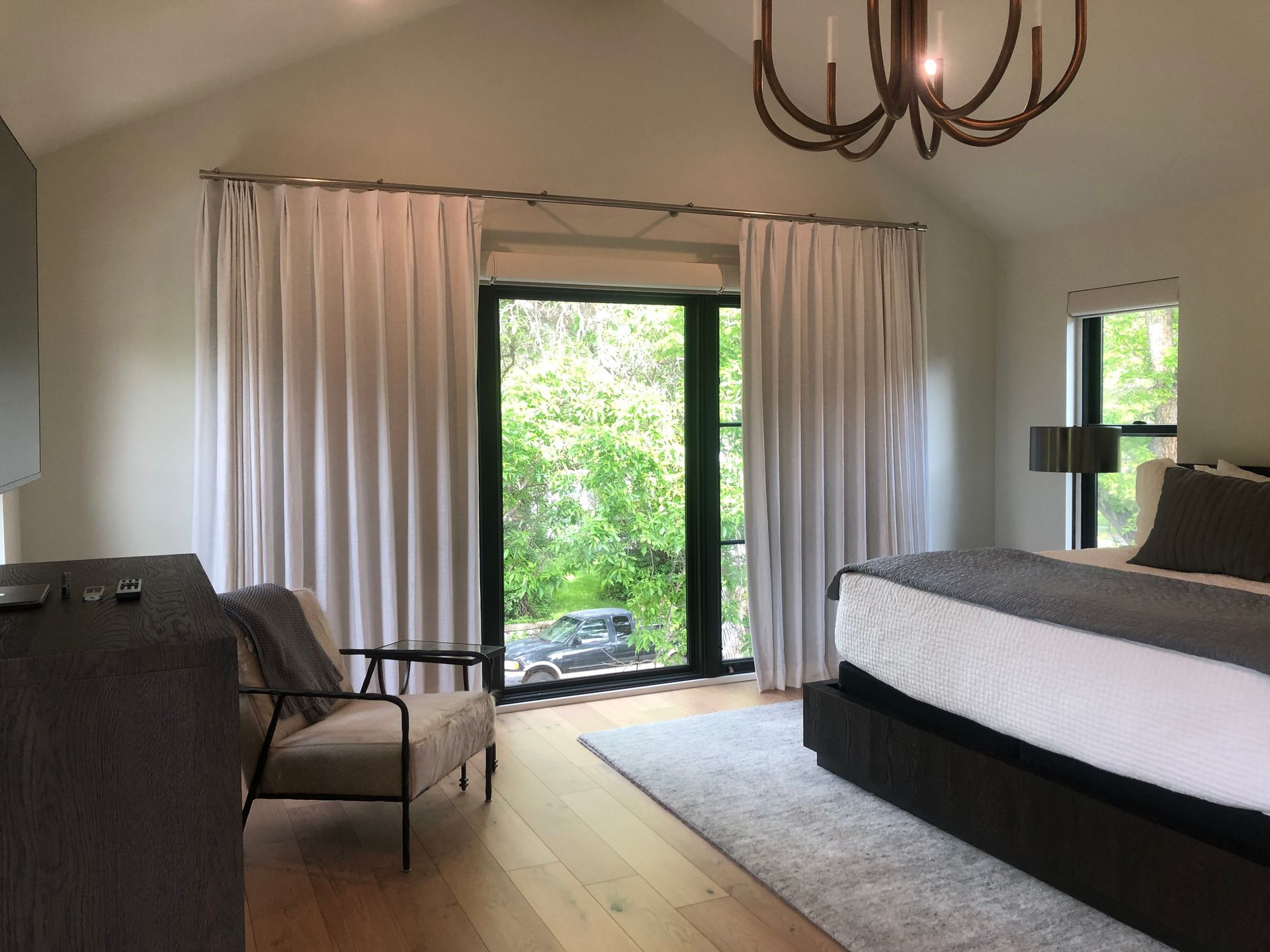 A bedroom with a bed , chair , dresser and window.