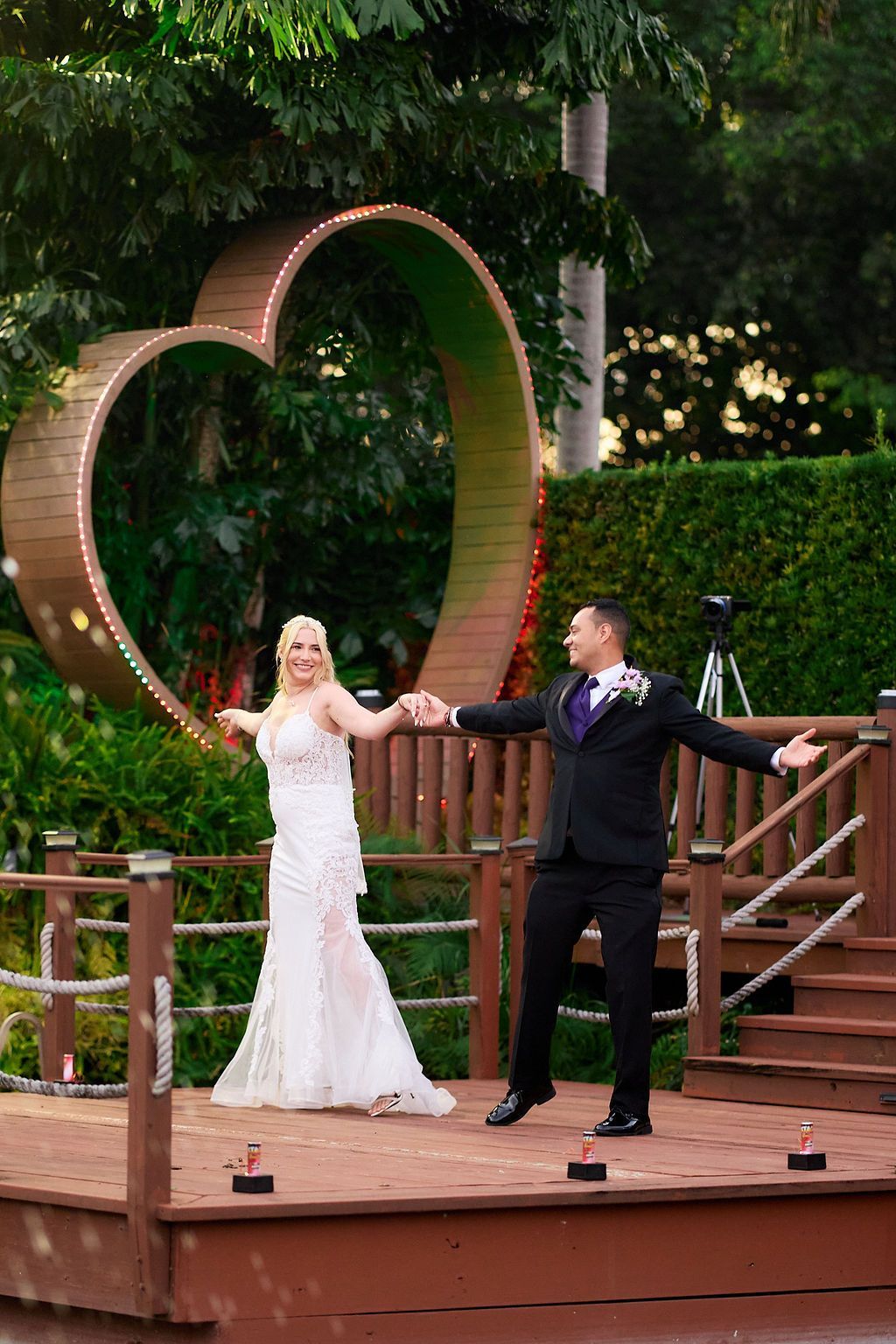 Bride and groom dancing on a wooden stage, heart-shaped backdrop.