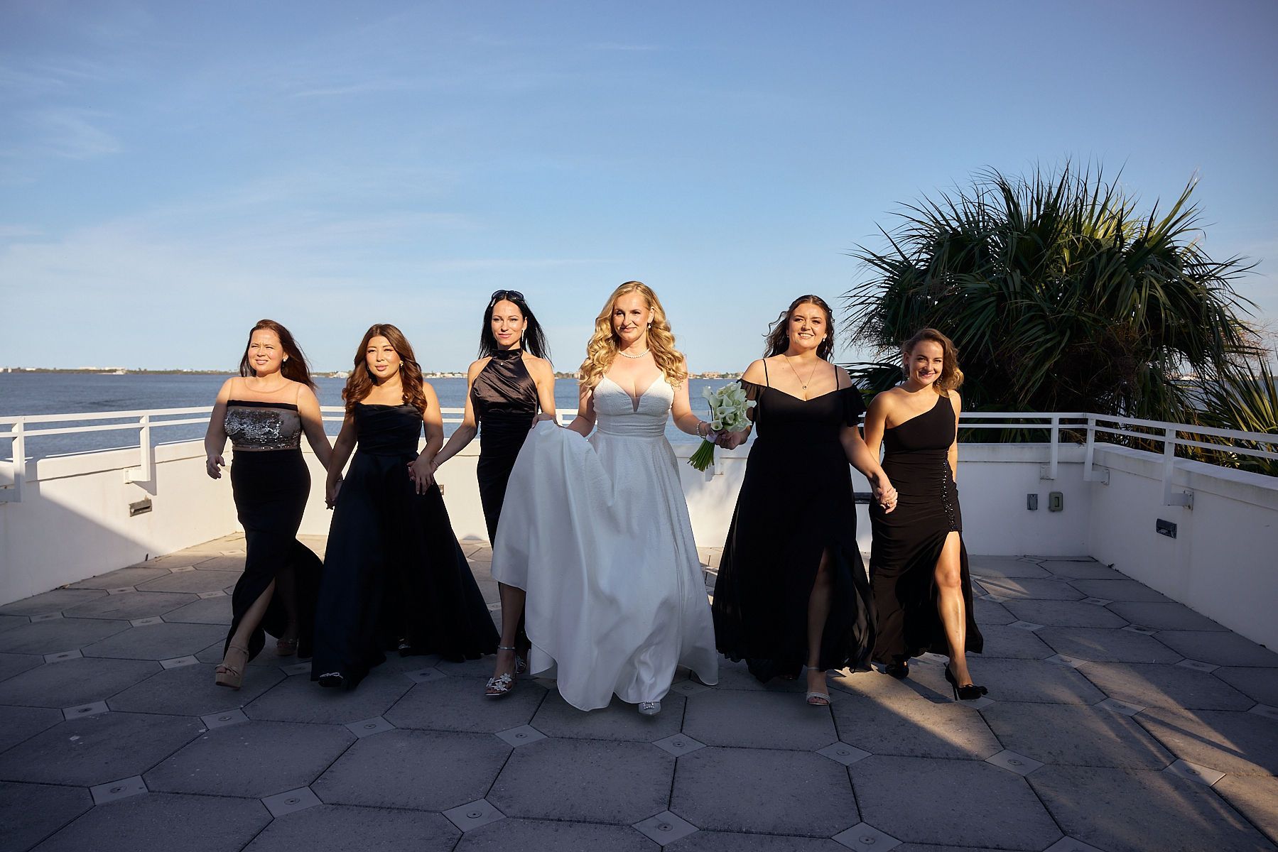 A bride and her bridesmaids are standing next to each other on a balcony.