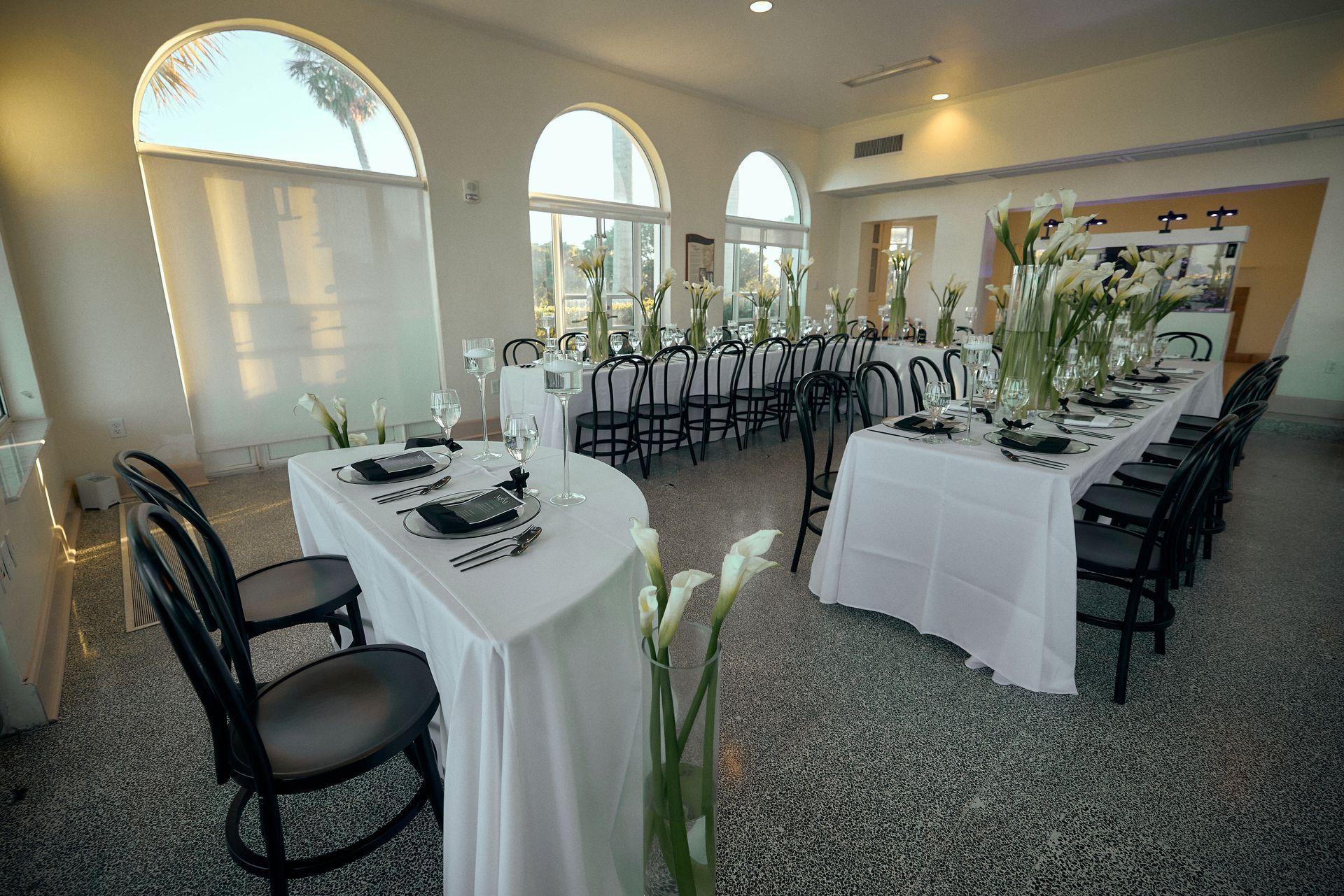 A large room with tables and chairs set up for a wedding reception.