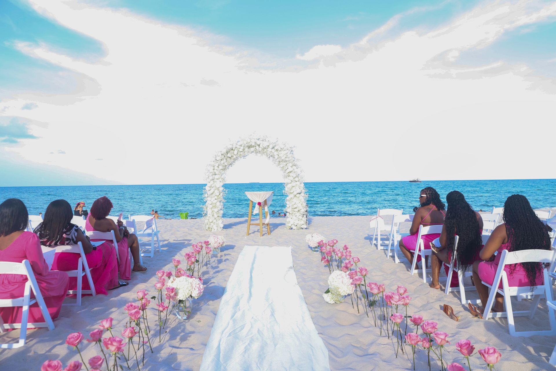 A group of women are sitting in chairs at a beach wedding.