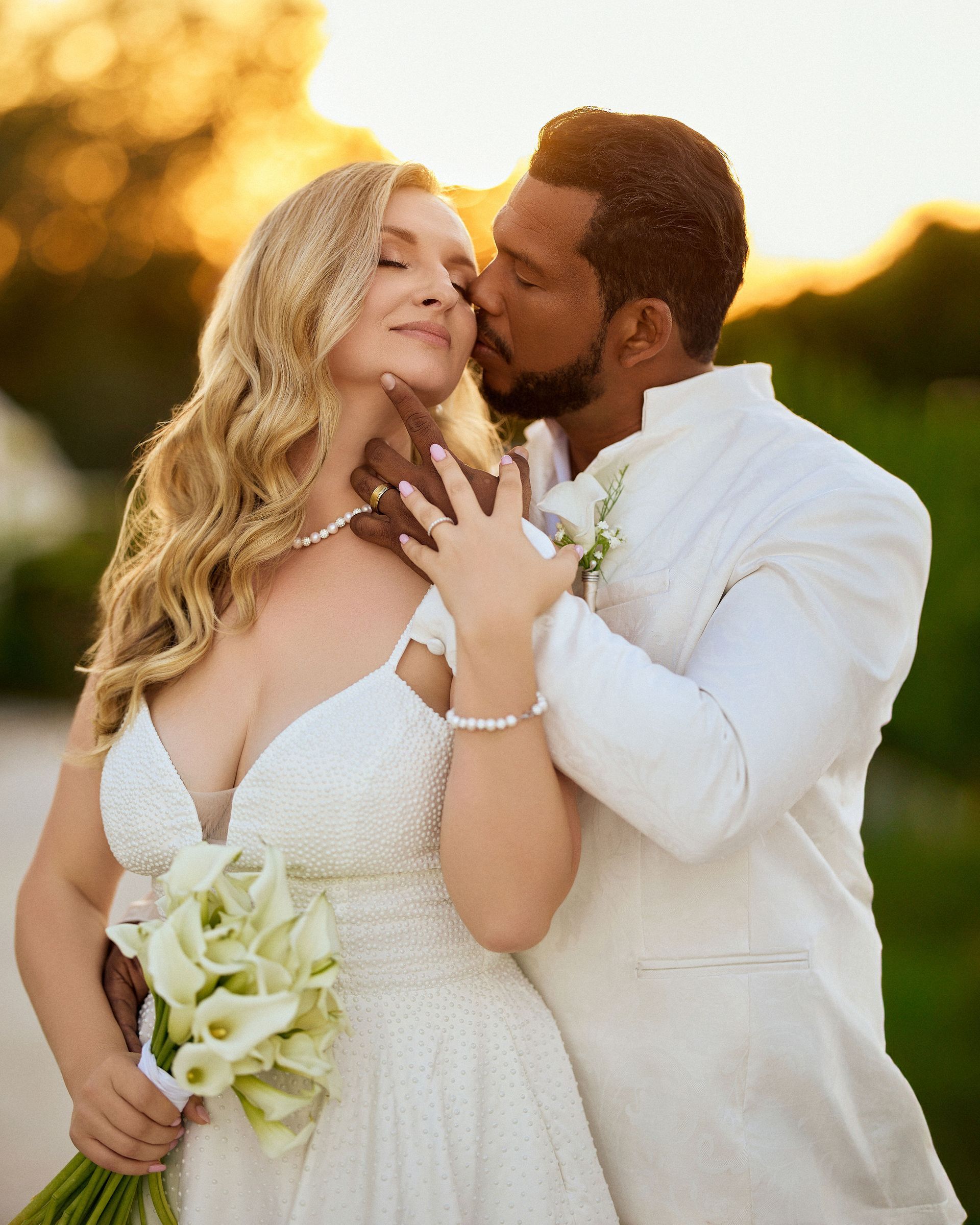A man is kissing a woman on the cheek while she holds a bouquet of flowers.