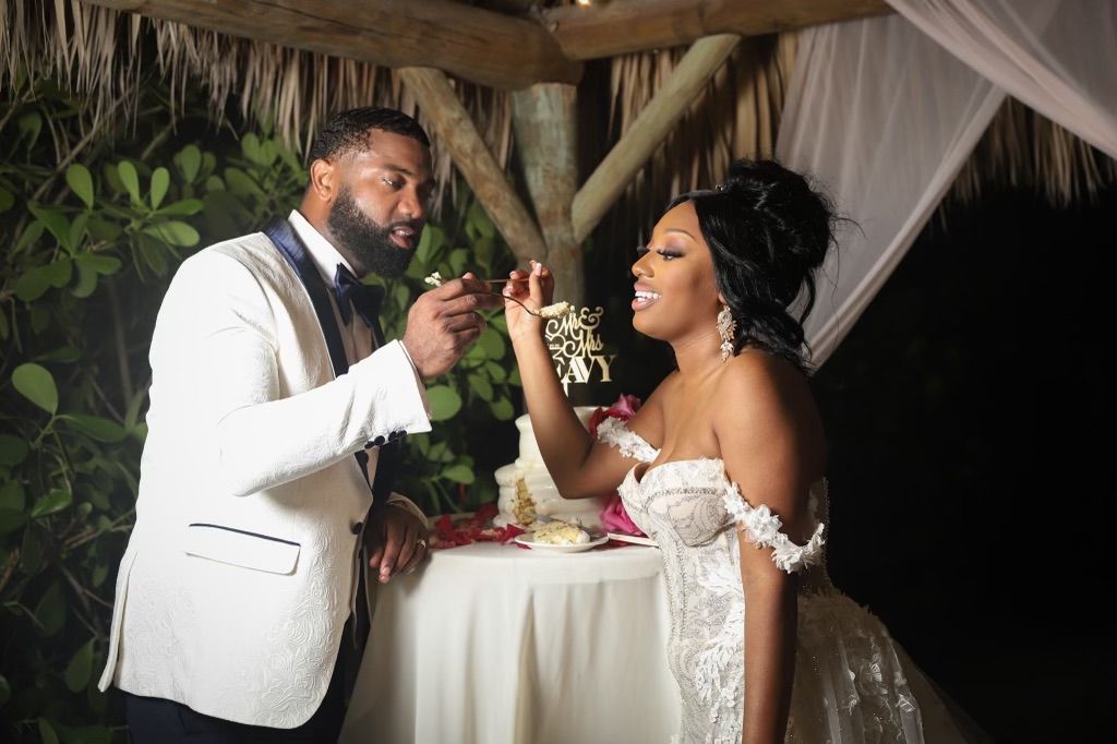 A bride and groom are standing next to each other at a table.