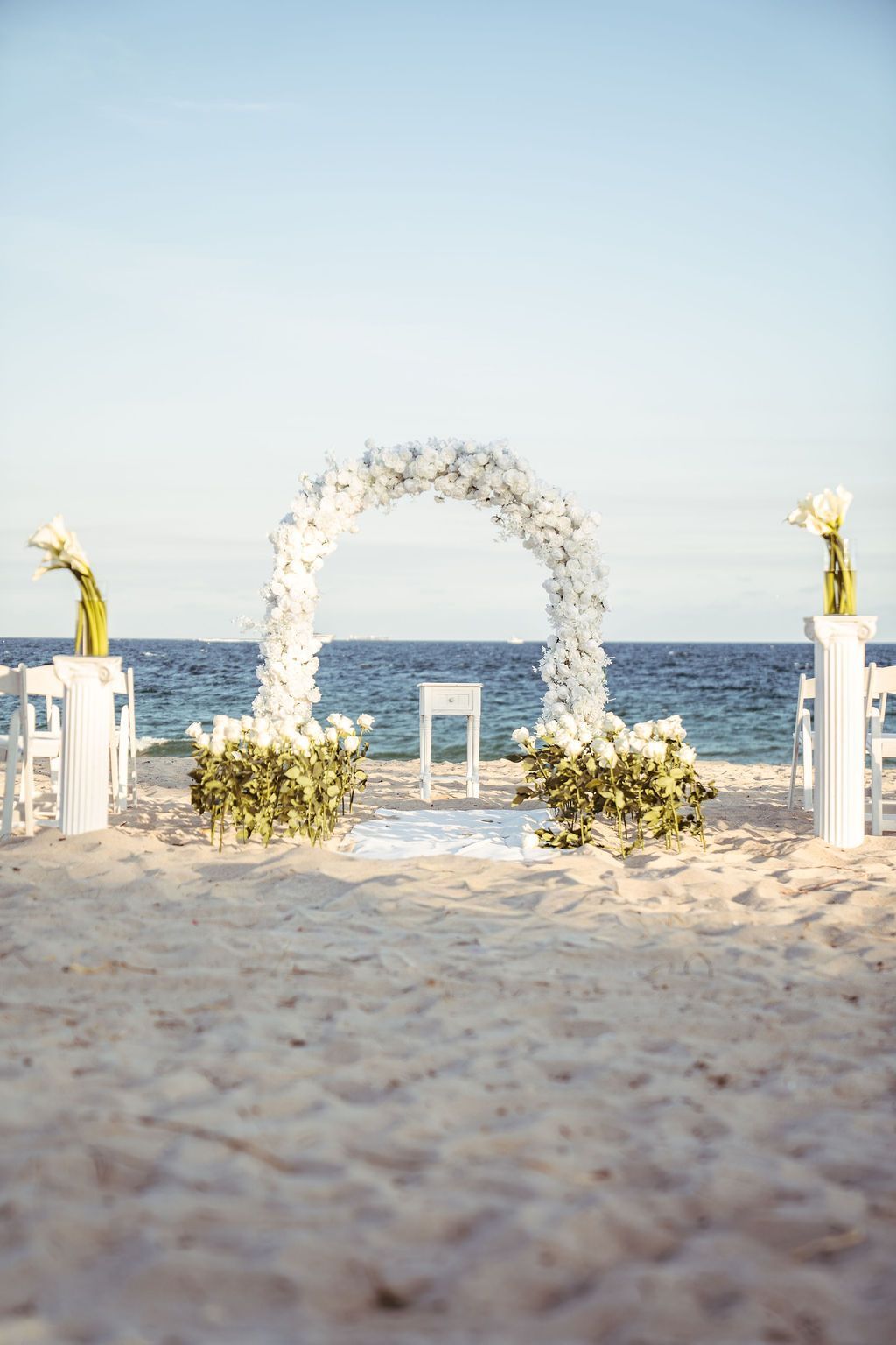 beach wedding set up in fort lauderdale with white floral garland and white roeses decor 