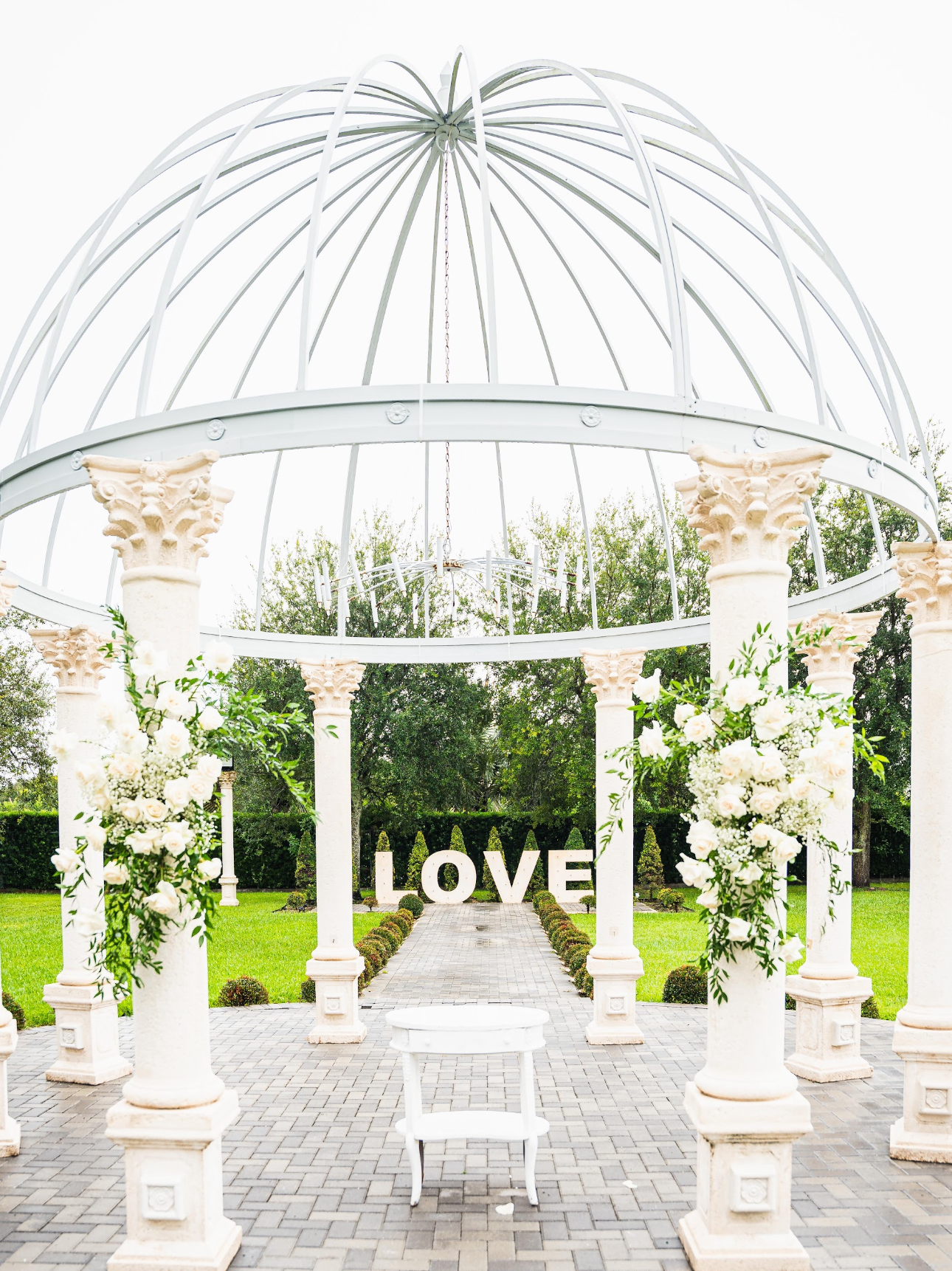 Wedding gazebo with white columns, flower arrangements, and 