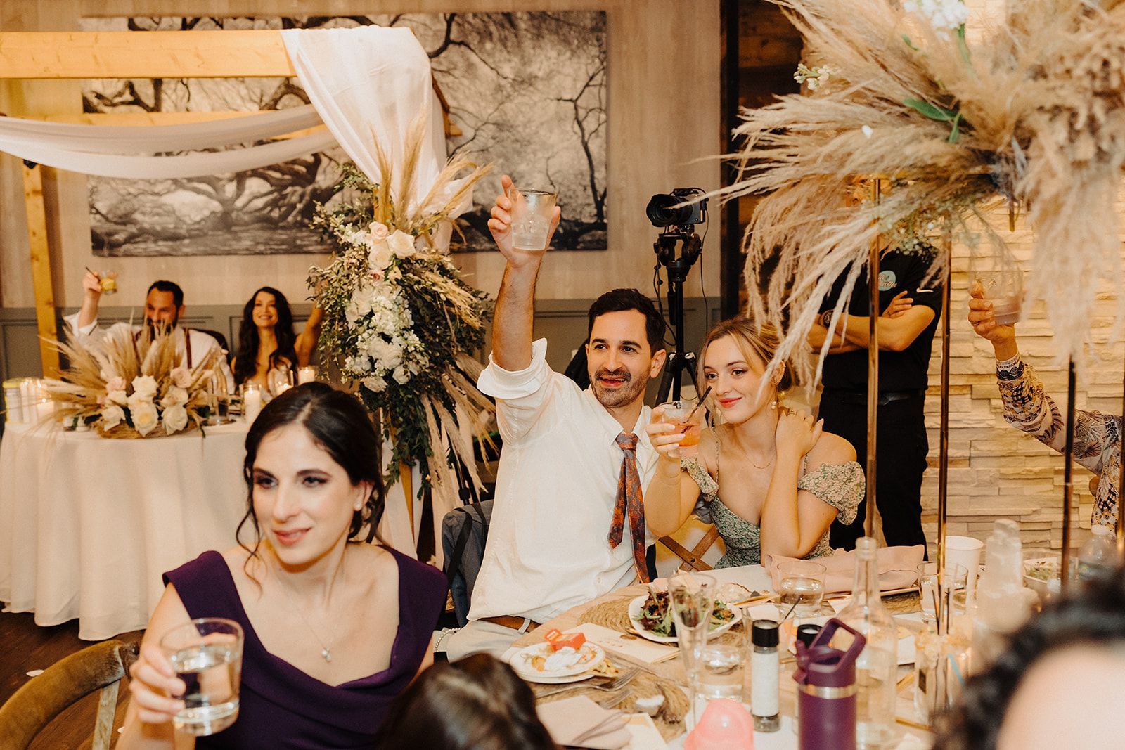 A group of people are sitting at a table toasting at a wedding reception.