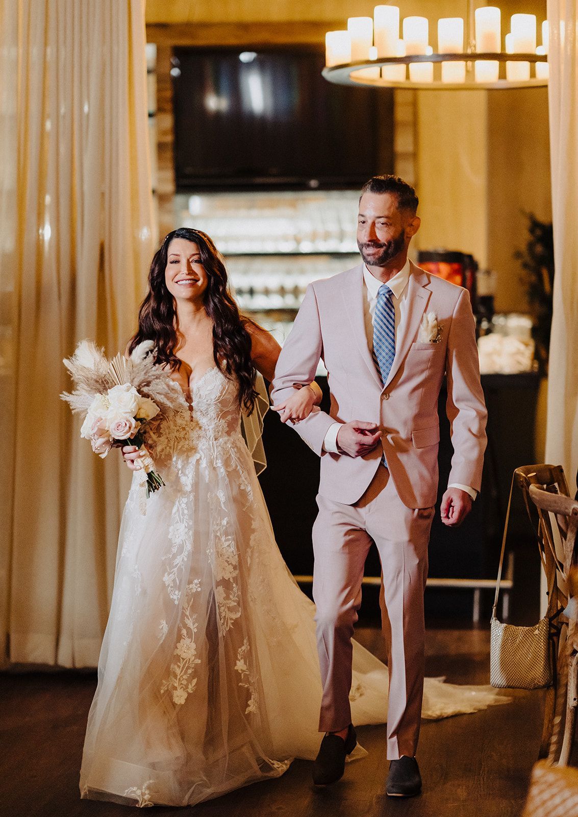 A bride and groom are walking down the aisle at their wedding reception.