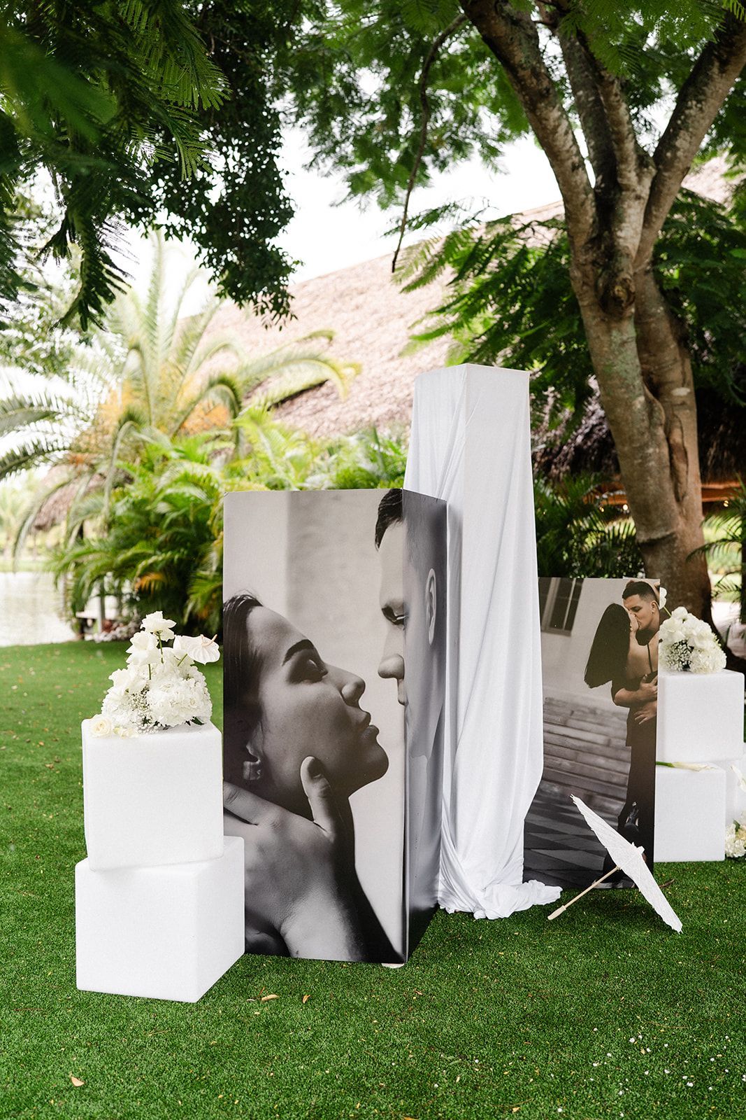Outdoor wedding photo display with black and white images, white accents, and greenery.