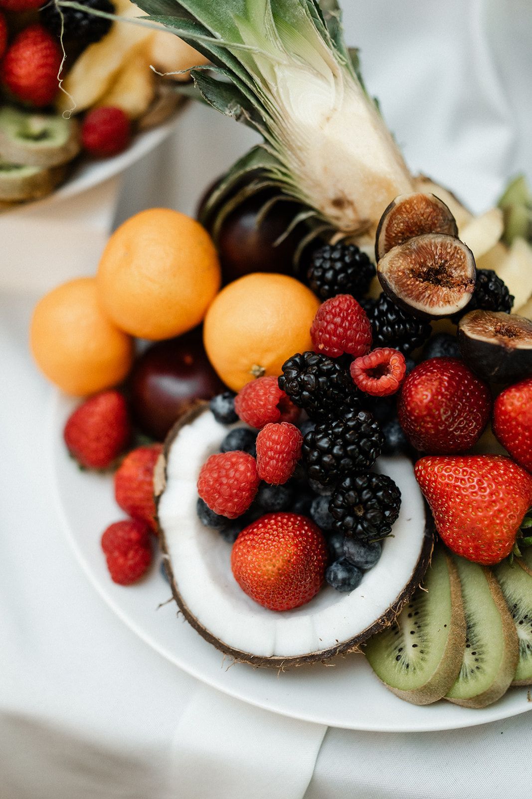 Fruit platter with strawberries, oranges, kiwi, berries, figs, and coconut.