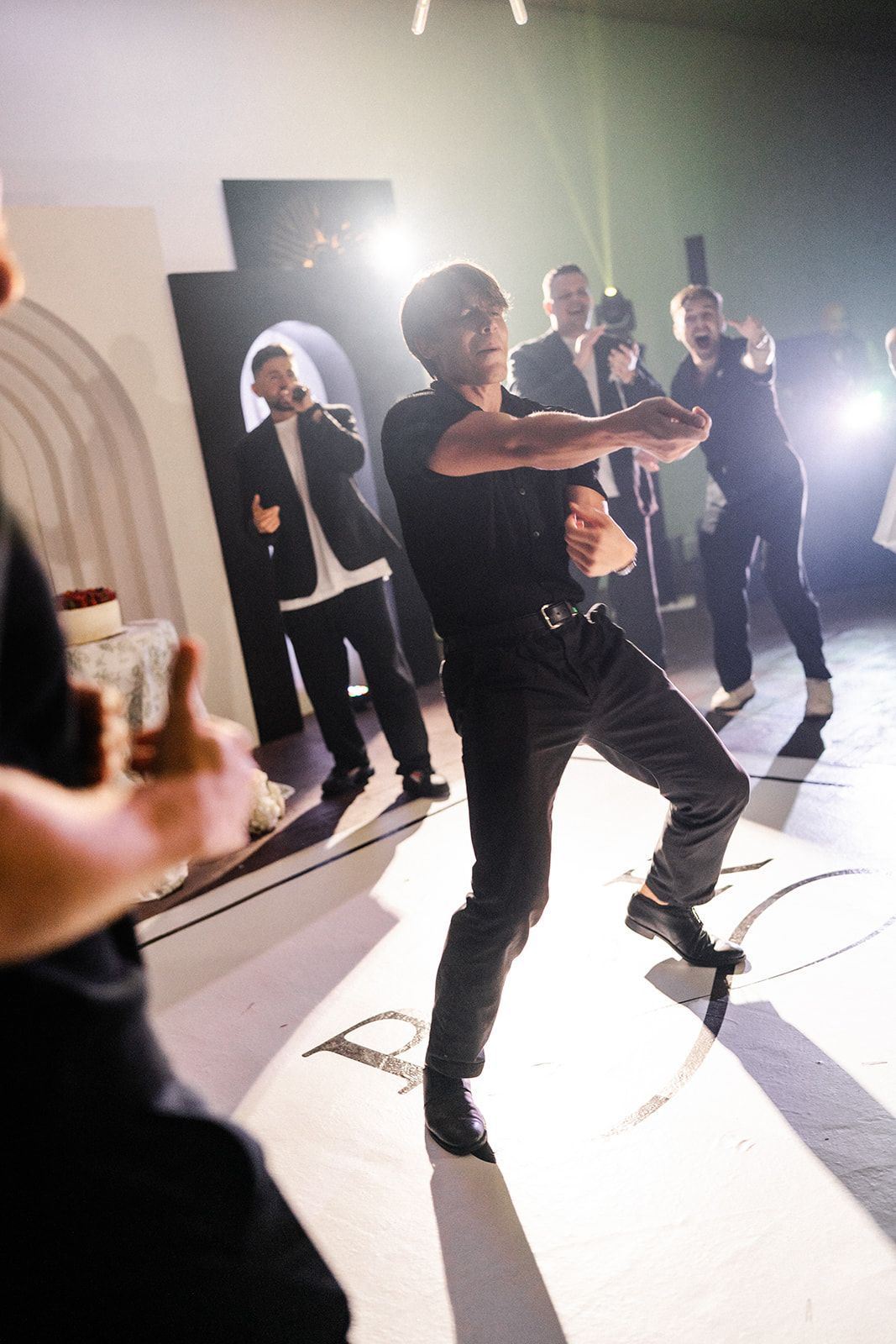 Man dancing energetically with a group of people in a brightly lit room.