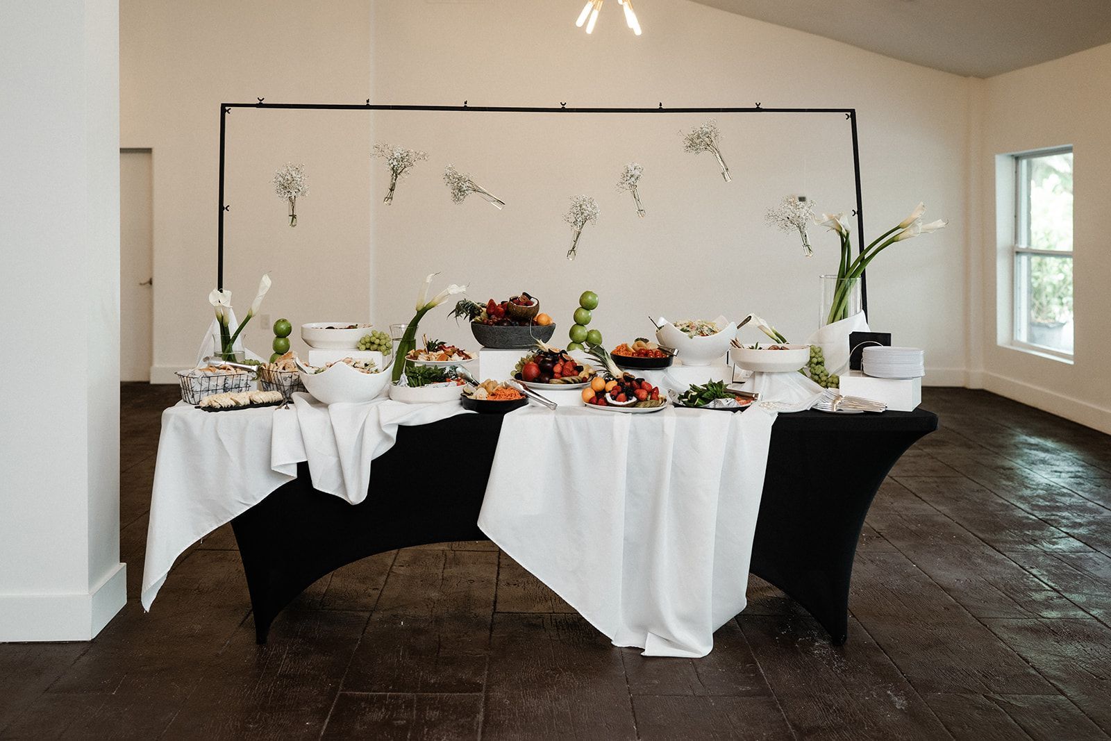 Buffet table with various dishes set against a black backdrop decorated with floral accents.